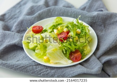 Creative image. Fresh vegetarian salad and grey napkin - stock photo