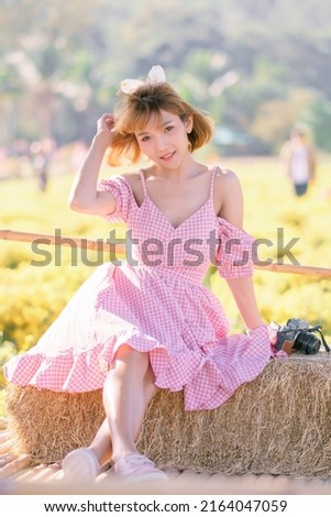 A beautiful Asian woman wearing a red dress is relaxing in a flower garden. In the afternoon, shooting in backlight, soft focus.