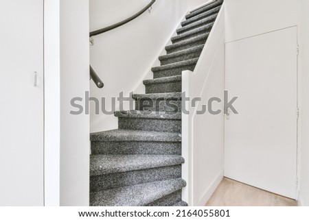 From above of narrow spiral stairway with white stairs and railing on wall inside of modern apartment