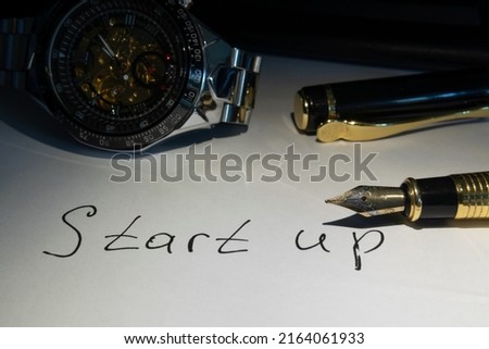 The inscription start up with a fountain pen. Calligraphy. Business plan. Pen, watch. Marketing analysis of the business. Planning goals and tasks. Accessories of a successful man. Close-up. skeleton