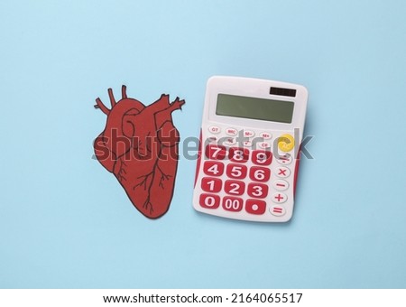 Anatomical paper heart and calculator on blue background. Top view