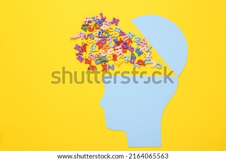 Open your mind, mental health concept, creative thinking. Paper silhouette of human head with letters on yellow background