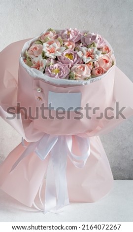 Zephyr bouquet of flowers in pink packaging on a gray background with a place for a business card