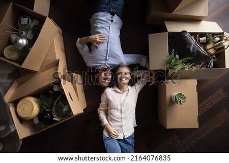 Beautiful couple in love lying on floor near heap of boxes with stuff resting on relocation or move-out day, top view. Bank mortgage for young spouses, cohabitation and relations, new house concept Royalty-Free Stock Photo #2164076835