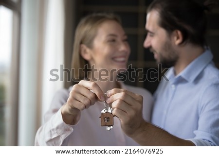 Relocation day, cohabitation, new house for young family, bank loan, happy clients of new first real-estate purchase concept. Blurred married 30s couple holding keys showing to camera close up view Royalty-Free Stock Photo #2164076925