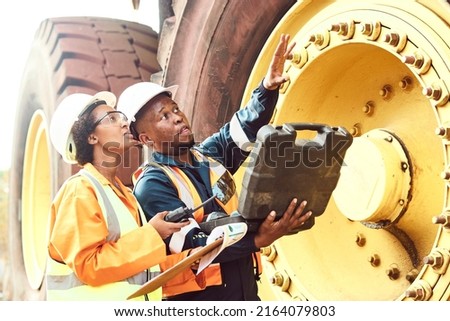 Two African Mine workers are discussing maintenance on a large haul dump truck Royalty-Free Stock Photo #2164079803