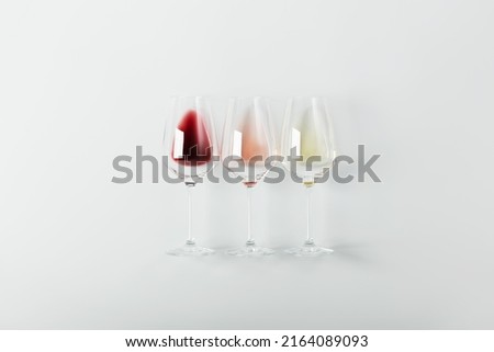 Flat-lay of red, rose and white wine in glasses on white background. Wine bar, winery, wine degustation concept. Minimalistic trendy photography Royalty-Free Stock Photo #2164089093