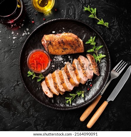 Roasted duck breast served with sauce and fresh herbs. Black background, top view Royalty-Free Stock Photo #2164090091