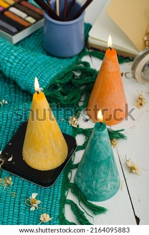 Set of burning candles on light background. Melted wax candles with elegant conic original form burning at holiday white table. Festive mood and atmosphere.