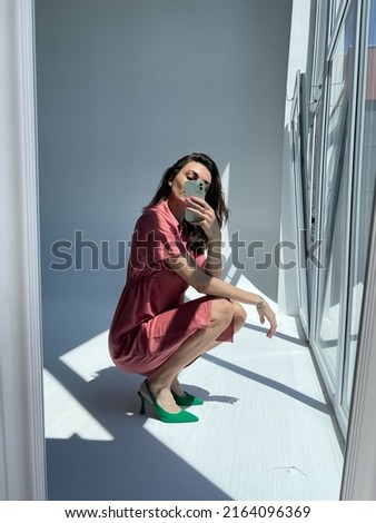 Fit tanned woman in comfy cotton summer long cute dress and green heels, take photo selfie on phone in mirror for social media, stories, vertical	