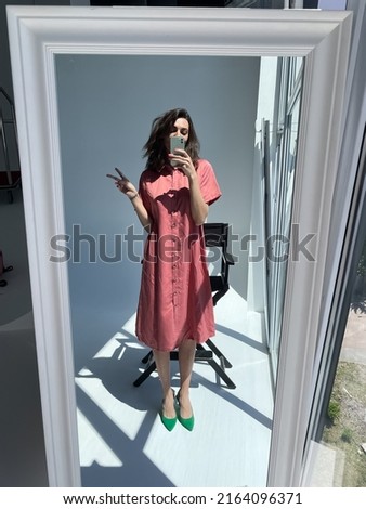 Fit tanned woman in comfy cotton summer long cute dress and green heels, take photo selfie on phone in mirror for social media, stories, vertical	