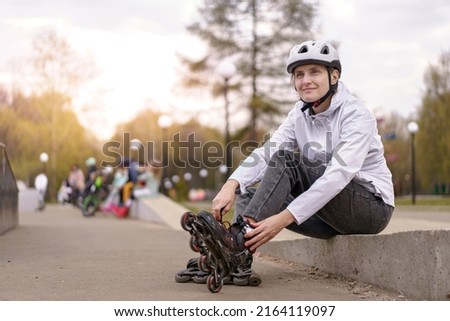 woman putting on roller skates outdoors. The concept of a healthy lifestyle and sports leisure