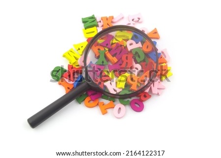 Many colorful wooden letters under magnifying glass isolated on white background. Study and education concept.