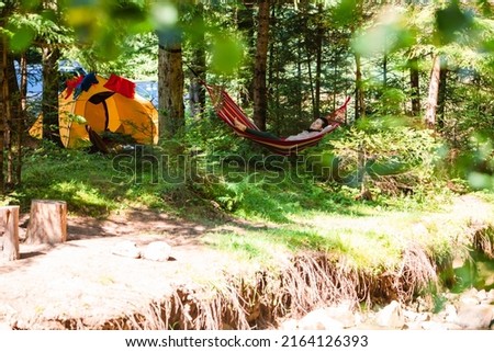 woman laying down in hammock in the forest tent on background copy space summertime