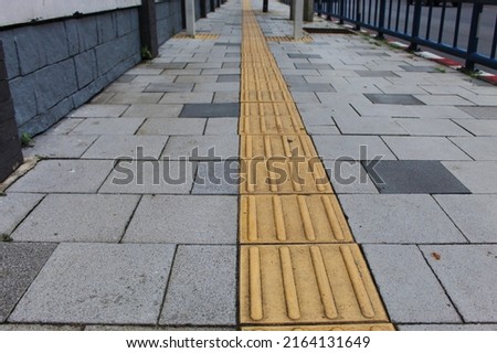 public walkway surface  For the visually impaired is a rough yellow tiled floor.  so that people with disabilities can walk the path and not cause harm