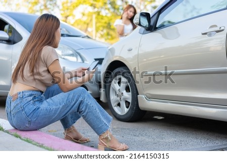 Two drivers check for damage after a car accident before taking pictures and sending insurance. Online car accident insurance claim idea after submitting photos and evidence to an insurance company.
