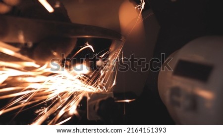 Sharpening the blade of an iron knife. Grinding machine. Grindstone. Sparks. Work in the workshop. production. Metalworking. Male hands in gloves. close-up.