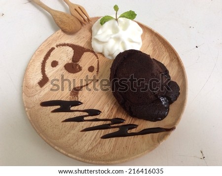 molten lava chocolate cake with whipping cream and penguin cartoon from coco powder as decoration on wooden dish