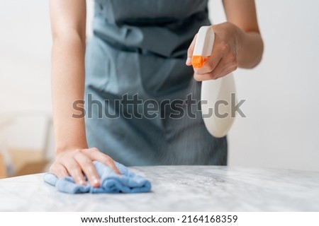 Cleaning hygiene, asian young maid woman, girl hand in using a water sprayer bottle to wipe clean, use blue rag wiping to dust on white marble table in restaurant. Housekeeping cleanup, cleaner. Royalty-Free Stock Photo #2164168359