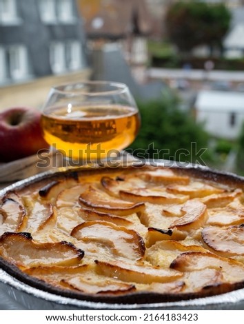 Apple products of Normandy region, homemade baked apple cake and cider drink and houses of Etretat village on background, Normandy, France