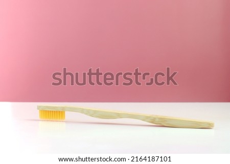 one toothbrush lies on a pink background, an eco-friendly brush on a white table