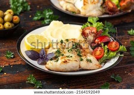 Fried cod loin fillet with mashed potato and vegetable salad served with fresh lemon