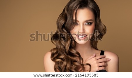Beautiful brunette model  girl  with long curly  hair . Smiling  woman hairstyle wavy curls .  Fashion , beauty and makeup portrait Royalty-Free Stock Photo #2164193583