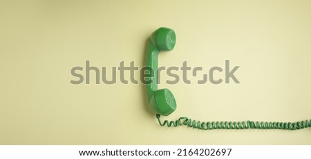 Green Vintage Retro Telephone Handset Hanfing on Pink background. Old Object from 1980-1990, Technology and Communication in the Past. Clean, Colourful  and Minimal