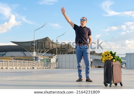A man with luggage meets passengers at the airport car park. Business trip, vacation