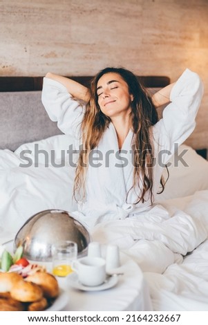 Woman eating breakfast in the hotel room. Room service breakfast in hotel room.  Royalty-Free Stock Photo #2164232667