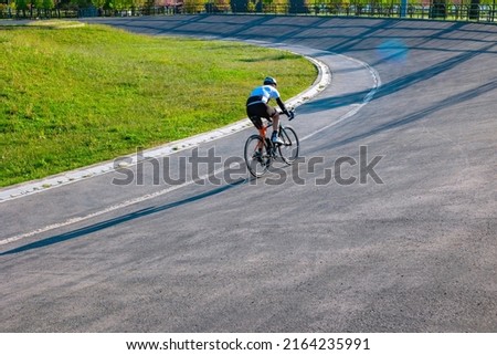 Cyclist training on the cycle-racing track in the park. Biker or bicycle sports or training or exercising or healthy lifestyle background photo. Motion blur on the cyclist.