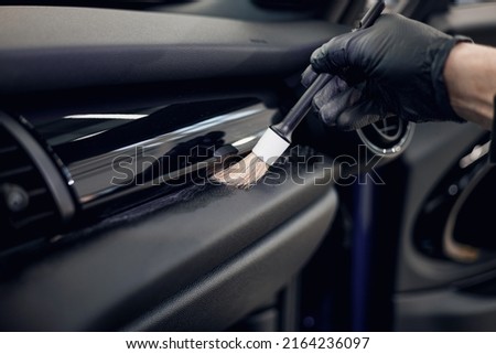 Cleaning the car interior with a brush. Auto detailing worker cleaning car interior, car detailing concept. Selective focus. Dust removal from the dashboard of the car with a brush Royalty-Free Stock Photo #2164236097