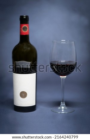 Opened dry, red wine and exclusive wine glass. (Whole picture with smoke and grey background)