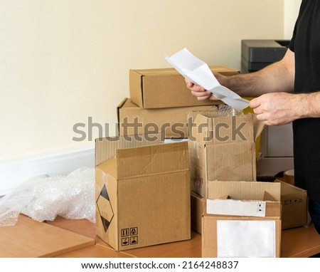 a man takes out documents from the delivered parcels boxes in his office. copy space.