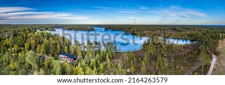 Breathtaking Aerial Panorama of Scandinavian green pine tree forest, dark blue lake with few small islands, Baltic Sea on horizon. Sunny day, Northern Scandinavia