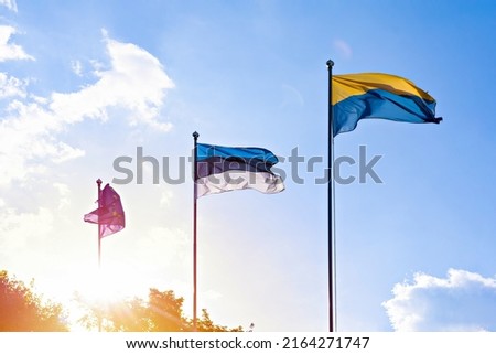 Three waving flags: Ukrainian, Estonian and European union on blue sky in sunlight. Ukrainian independence day. Ukrainian military. Pray Ukraine