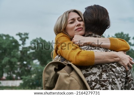 Depressed woman hugging her husband before leaving on war Royalty-Free Stock Photo #2164279731