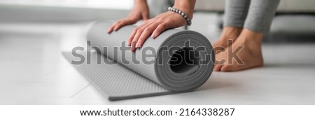Yoga online class at home woman rolling mat on apartment floor for gym training or meditation banner panoramic. Feet and hands closeup Royalty-Free Stock Photo #2164338287