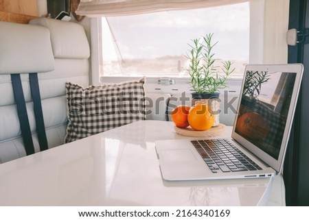 Concept of alternative travel office lifestyle with modern laptop on a camper van table. Digital nomad lifestyle with computer inside motor home. Wireless technology for traveler people