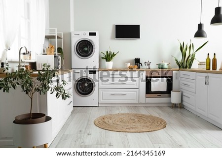 Stylish interior of kitchen with modern washing machines Royalty-Free Stock Photo #2164345169