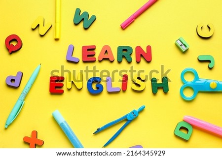 Text LEARN ENGLISH with letters and stationery on yellow background