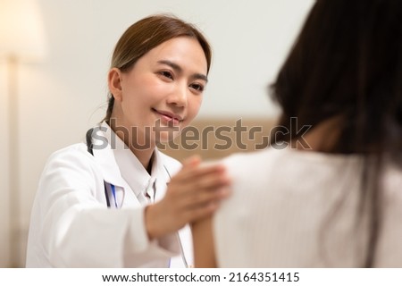 Asian female doctor giving hope and encourage to stressed woman patient at hospital. Smiling doctor woman touching on patient shoulder to support take care and helping . Supported and Encouraged Royalty-Free Stock Photo #2164351415