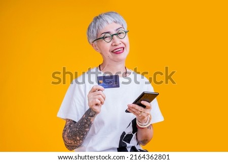 old senior asian woman tattoo hand show credit card and smartphone with smile confident and cheerful asia old woman grey hair standing hand gesture hold credit care cashless payment business ideas
