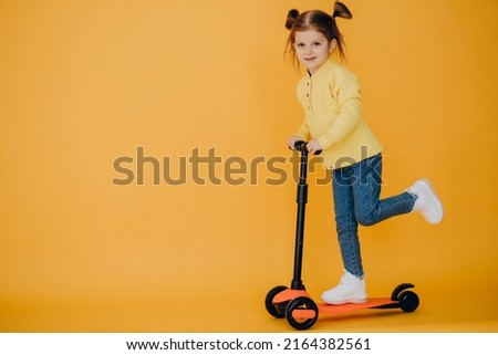 Little girl riding scooter in studio