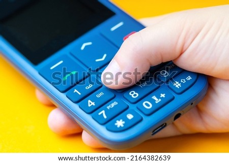 Kid's hand dialing number on a push-button cell phone. Macro photography. Royalty-Free Stock Photo #2164382639