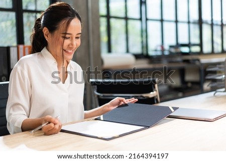 Asian business female project manager reading document report at desk in the office. work data and information. signing on business contract agreement.