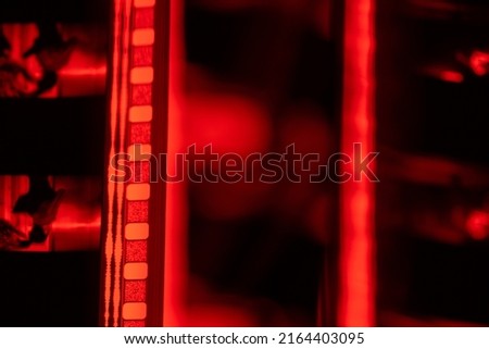 Vintage filmstrip in soft red light. Analog old strips of film for a photo or video camera close up. The concept of cinematography, photography, photographic memories.