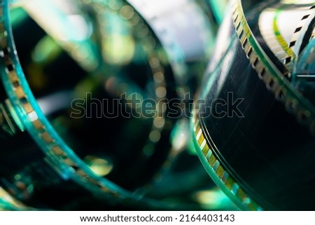 Spiral retro film strip in soft green light. Twisted analog old strips of film for a photo or video camera close up. The concept of cinematography, photography, photographic memories.