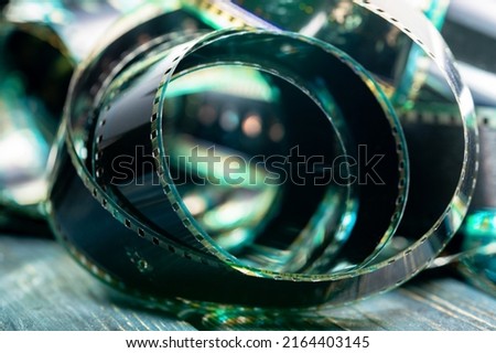 Spiral retro film strip in soft green light. Twisted analog old strips of film for a photo or video camera close up. The concept of cinematography, photography, photographic memories.