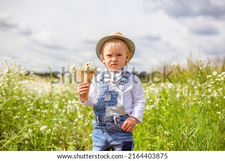 Portrait of adorable baby with flowers in chamomile field